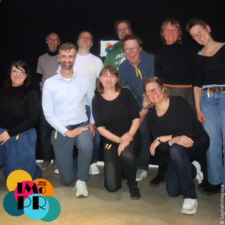 Die Afterwork Impro Allstars haben gezeigt, was entsteht, wenn Spielende aus unterschiedlichen Ensembles für einen Abend zusammenkommen: Ein einmaliges Zusammenspiel, das es so noch nie gab – und so auch nie wieder geben wird. Anfang Mai ging die Afterwork Impro Allstars Show in die zweite Runde – in Niendorf im wunderbaren The Village. Es war eine rasante Improtheater-Show mit Games, Comedy und jeder Menge Spaß! Auf dem Bild siehst du die 10 Mitglieder der Allstars-Gruppe, 5 Frauen und 5 Männer, die in zwei Reihen vor einem schwarzen Vorhang stehen und knien und nach erfolgreicher Show in die Kamera lächeln. Mit Afterwork Impro in den Feierabend starten, entdecke Improvisationstheater an coolen Orten! Afterwork Impro aus Hamburg veranstaltet Business- und Freizeit-Workshops mit den Methoden des Improtheaters.